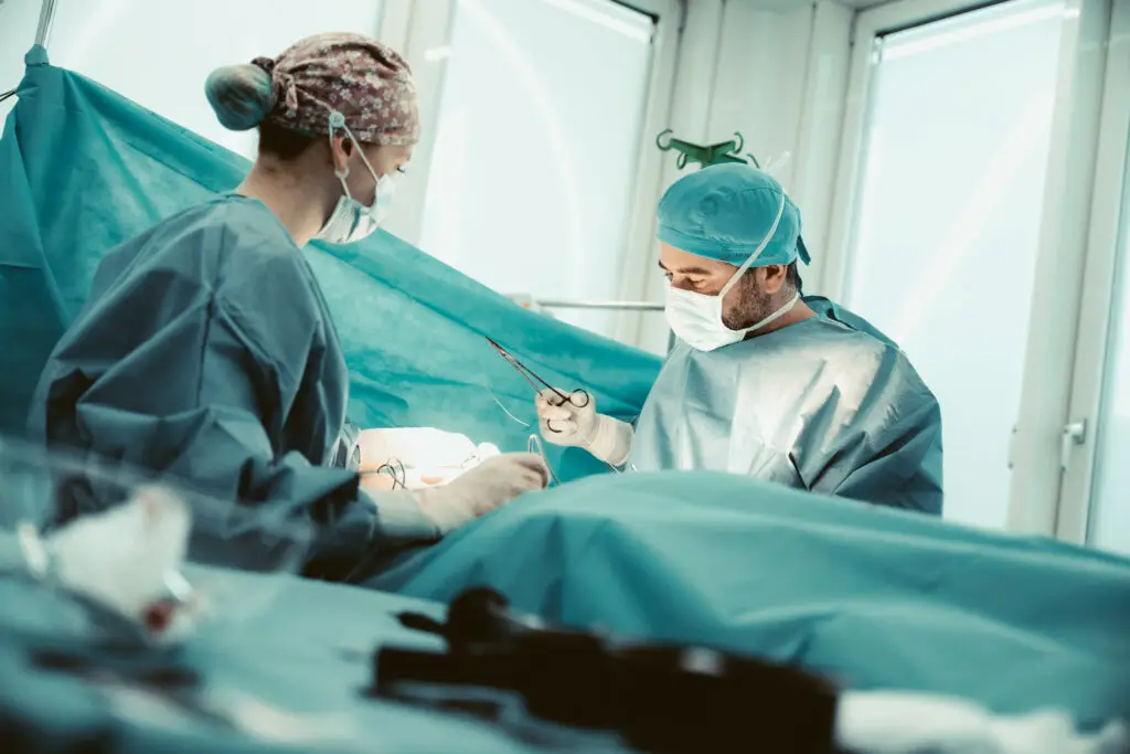 Zwei Operateure mit chirurgischem Instrument während einer Operation