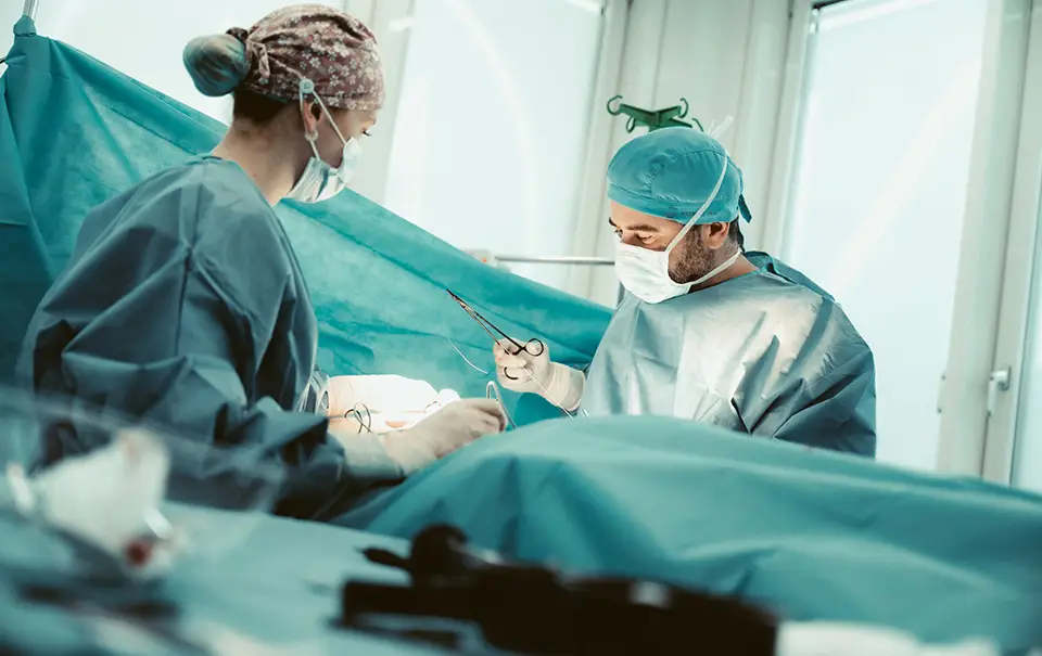 Zwei Chirurgen in OP-Kleidung während einer Operation mit chirurgischen Instrumenten