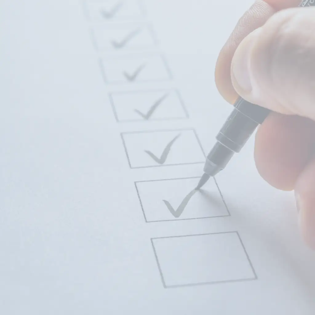 Hand hakt mit einem Stift die Kästchen einer Checkliste ab