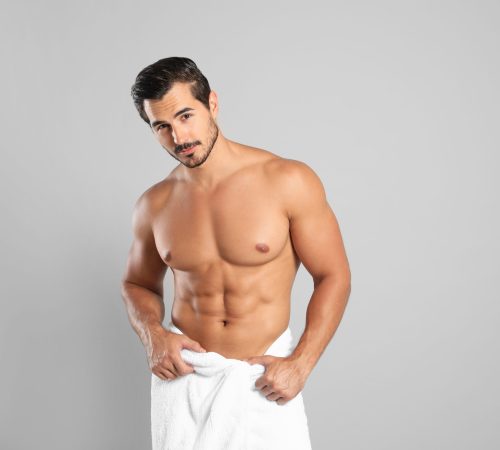 Young man with slim body on grey background